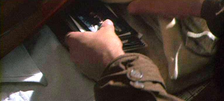 Figure 18: Blade Runner. Examining Leon’s apartment a trench-coated Deckard finds photographs in a drawer. His un-gloved hands—in contrast to the films above—symbolize that he is beginning to ‘feel’ for the Replicants he is supposed to kill.